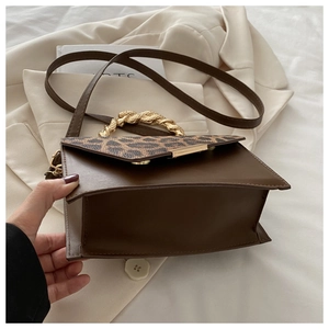 Detail of square brown bag with leopard print flap and golden braided metal handle