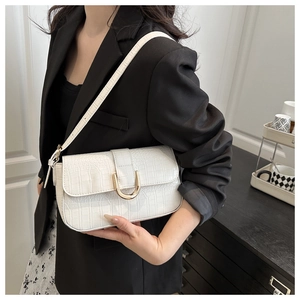 Detail of white crocodile pattern shoulder bag with a gold U-shaped metal buckle