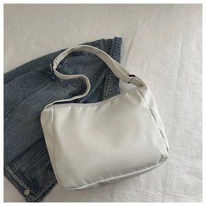 Top view of white nylon tote bag with adjustable strap on blue denim and quilted fabric
