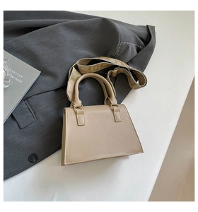 Detail of beige square handbag with circular handle and patterned wide shoulder strap