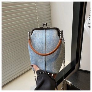 Détail du sac à fermoir en denim avec strass brillants, poignée en cuir et bandoulière