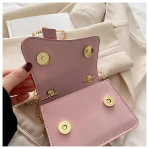 Close-up of pink flap bag showing four gold magnetic snap buttons and chain strap
