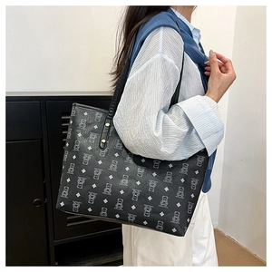 Detailed view of the cute bear pattern and gold metal hardware on the black tote bag