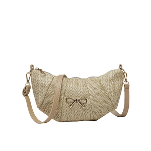 Woven crescent shoulder bag in light beige straw with gold bow accent and leather strap