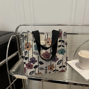 Fashionable floral brocade tote bag for women with black handles on a modern silver stand