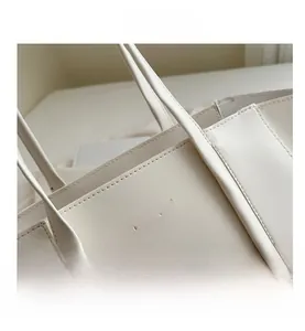 Detailed close-up of white leather tote bag featuring fashion embossing and fine stitching