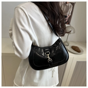 Gros plan d'un sac à bandoulière en cuir noir brillant avec boucle mousqueton dorée
