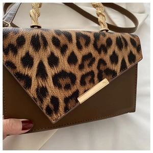 Close-up of leopard print patchwork flap on brown leather handbag with gold metal handle