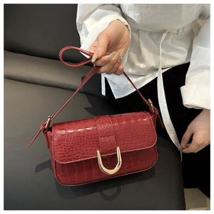 Detail of red crocodile texture leather shoulder bag with golden U-shaped buckle