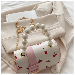 Detail of white cherry print handbag with large pearl handle and gold chain strap