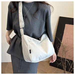 Minimalist white nylon crescent crossbody bag worn by model for daily casual commute style