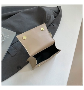 Detail view of the beige crossbody bag interior with dual gold magnetic buckle closures