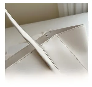 Macro shot of precise stitching and premium leather texture on ivory tote bag
