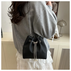 Détail du sac seau noir à cordon avec texture plissée et perles sur une chaîne en argent
