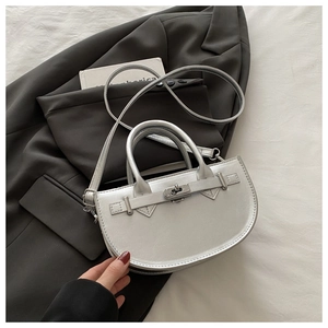 Gros plan d'un sac demi-lune argenté avec fermoir métallique sur une veste de costume