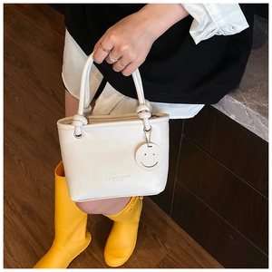 Detail of white PU leather tote with smiley charm and elegant embossed fashion text