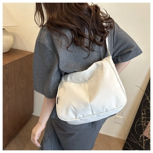 Detailed back view of a minimalist white canvas crossbody bag worn in a cozy indoor setting