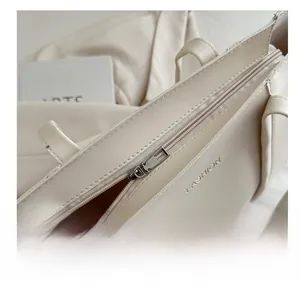 Macro detail of silver metal zipper and embossed Fashion text on beige leather tote bag