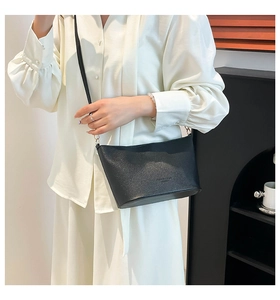 Détail du sac bandoulière en cuir grainé noir avec logo embossé et fine bandoulière