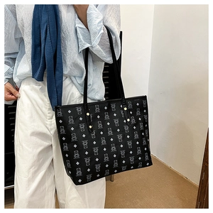 Detail of black tote bag with white bear pattern and gold rivets worn on shoulder