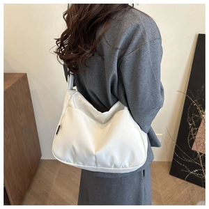 Detail showing the white nylon half-moon shoulder bag with a functional front pocket
