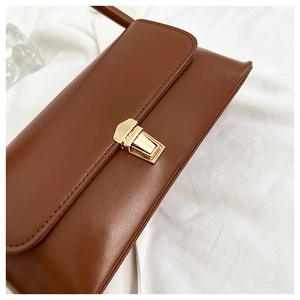 Detailed macro view of brown leather bag featuring an elegant gold square metal buckle