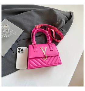 Close-up of fuchsia quilted handbag with gold metal V-clasp and stylish tassel detail
