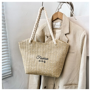 Detail of woven straw tote bag with Fashion xing embroidery and thick cotton rope handles