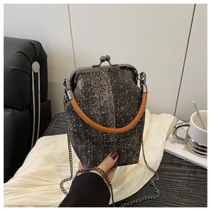 Detail of tweed bucket bag with metal clasp, leather handle and silver chain strap
