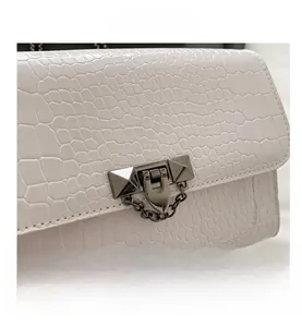 Macro detail of white crocodile pattern shoulder bag with a gold rivet metal lock