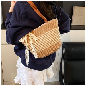 Detailed side view of striped straw tote bag featuring a white lace bow and brown leather strap