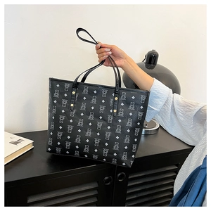 Detail of cute bear monogram print on black tote bag with silver rivets and leather straps
