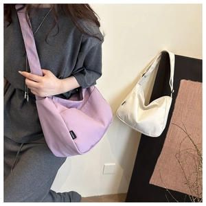 Detail of soft purple canvas crossbody bag with wide strap and branded fabric label