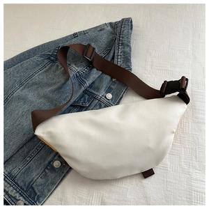 Detail view of white nylon crescent bag with adjustable brown strap and yellow accents