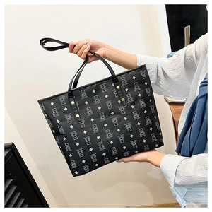 Close-up of black leather tote bag with white bear prints and gold rivet details