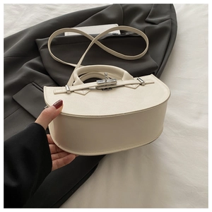 Détail macro du sac à main demi-lune en cuir PU blanc crème avec fermoir rotatif argenté