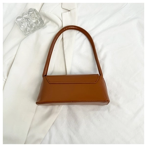 Top view of a caramel brown matte leather baguette bag on a white pleated fabric background