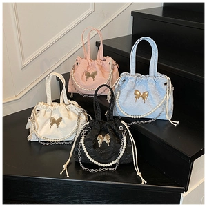 Detail of four colorful drawstring bucket bags with gold butterfly and pearl chains