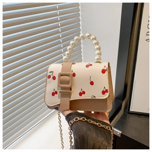 Detail of cherry print flap bag with large pearl handle and golden chain strap