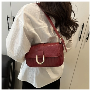 Detail of burgundy crocodile pattern shoulder bag with a stylish gold U-shaped buckle