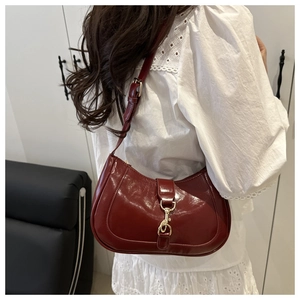 Détail du sac croissant en cuir verni bordeaux avec fermoir doré et tenue en dentelle