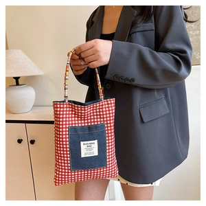 Détail du sac cabas en toile à carreaux rouges avec poche en denim et anse tissée