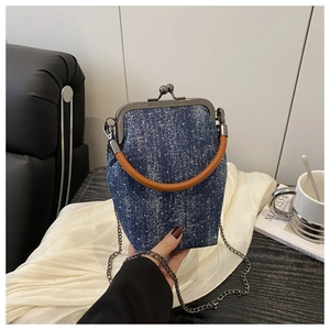 Detail of blue denim polka dot mini frame bag with silver metal clasp and chain strap