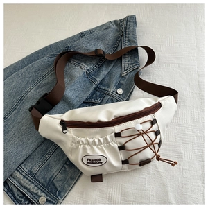 Détail d'un sac bandoulière en nylon beige avec fermetures marron sur une veste en jean