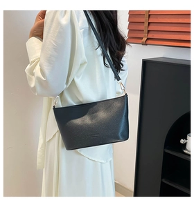 Détails du sac seau noir grainé avec boucle dorée et marquage fashion sur le cuir souple