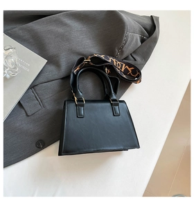 Detail of black leather handbag with a stylish orange textured wide shoulder strap