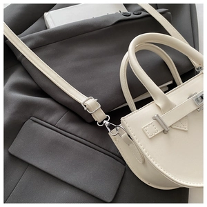 Détail de la texture cuir blanc crème avec boucle en métal argenté sur un costume gris