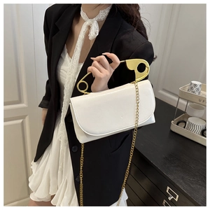 Dettaglio borsa in pelle PU bianca con esclusivo manico a spilla da balia dorata oversize