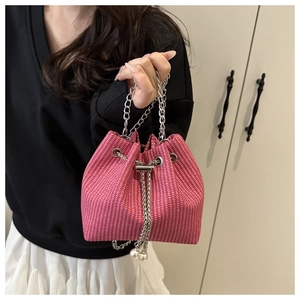 Détail du sac seau tissé rose avec chaîne argentée et breloques en perles blanches