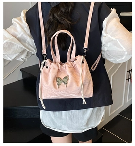 Pink satin drawstring backpack with metallic butterfly charm and white cord detail